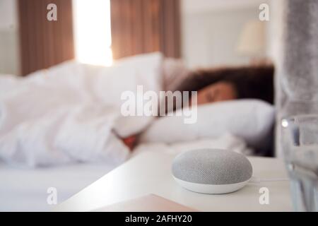 Woman Sleeping In Bed avec assistant vocal sur la table de chevet à côté d'elle Banque D'Images