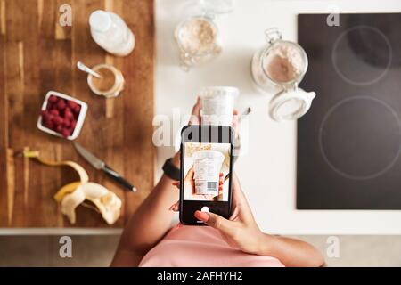 Femme portant des vêtements Fitness Scanning QR code sur l'emballage des aliments à trouver de l'information nutritionnelle Banque D'Images