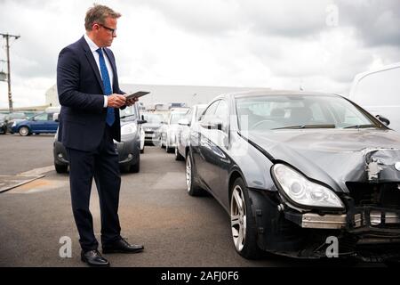 Sinistres Assurance mâle avec tablette numérique l'inspection des dommages au moteur de voiture Accident Banque D'Images