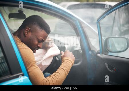 Automobiliste mâle blessé dans un accident de voiture avec airbag déployé Banque D'Images