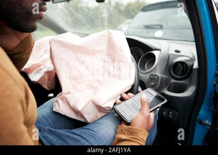 Automobiliste mâle blessé dans un accident de voiture après l'utilisation de téléphone mobile pendant la conduite Banque D'Images