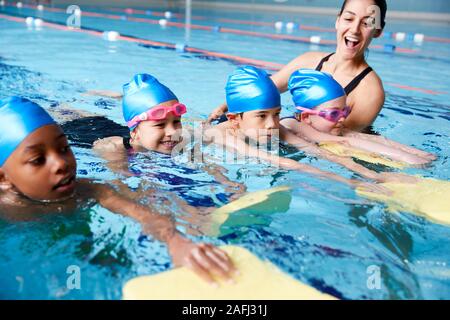 Entraîneuse en donnant de l'eau Groupe d'enfants leçon de natation en piscine couverte
