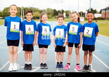 Portrait d'enfants sur piste d'athlétisme portant des numéros de concurrents sur la Journée des sports Banque D'Images