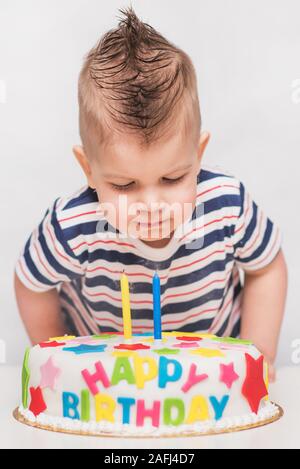 Un petit enfant souffle une bougie sur un gâteau pour son anniversaire Banque D'Images