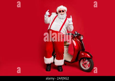 La taille du corps sur toute la longueur de sa vue il barbu nice cool joyeux joyeux Santa funky hipster debout près de moto corne double isolé signe montrant Banque D'Images