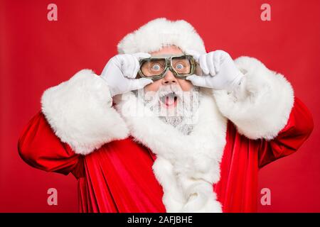 La photo en gros plan de l'impressionné funny santa claus touch son voyage lunettes turbo voir hiver discount vente portent des gants blancs cap hat isolated over Banque D'Images