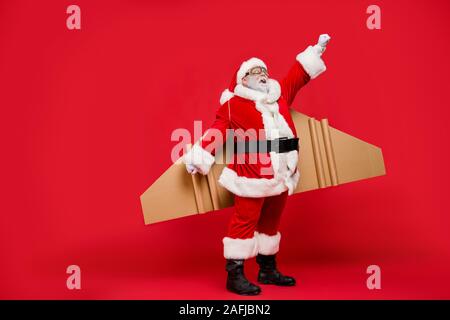 Photo pleine longueur de cheveux gris-personnes âgées santa spaceman impressionné par la magie des ailes pour voler jusqu'à usure vite eve cap hat isolated over red Banque D'Images