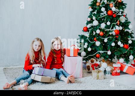 Deux petites filles blonde en robe rouge à cadeaux de noël vacances du Nouvel an Banque D'Images