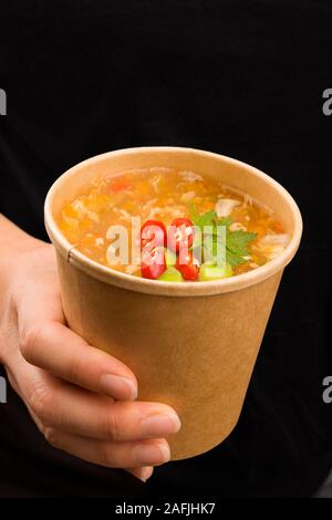 Belle femme de manger sur le pouce. Soupe aigre et piquante dans la tasse à emporter. Cousine traditionnelle asiatique. Banque D'Images