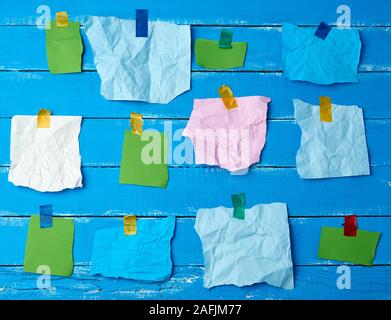 De nombreux morceaux de papier multicolores déchirés ou collés avec du scotch sur un fond en bois bleu, placez le texte Banque D'Images