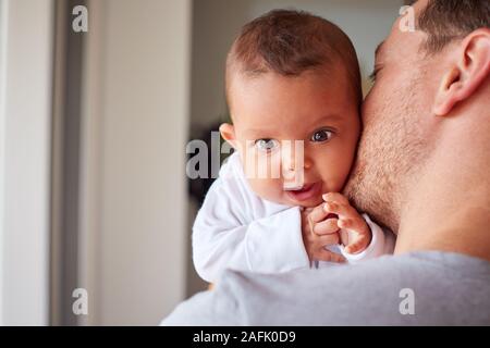 Portrait de bébé de trois mois fille étant détenu par le père aimant dans la cuisine à la maison Banque D'Images
