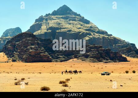 La Jordanie, Wadi Rum, caravane de chameaux et voiture dans le site du patrimoine mondial de l'Unesco au Moyen Orient Banque D'Images