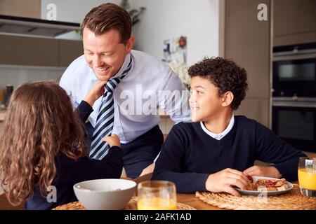 Homme d'aider fille père de mettre sur la cravate comme les enfants prennent un petit déjeuner dans la cuisine avant d'aller à l'école Banque D'Images