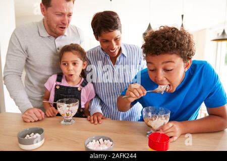 Famille en cuisine avec les enfants, source de consommation de crème glacée et desserts Banque D'Images