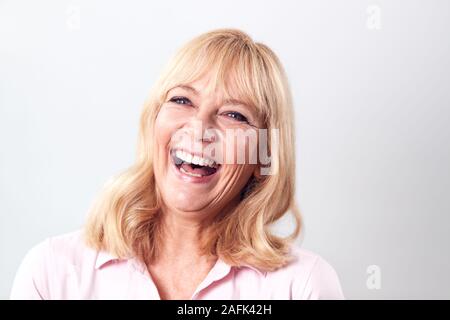 Studio Shot of Laughing Young Woman Against White Background at Camera Banque D'Images