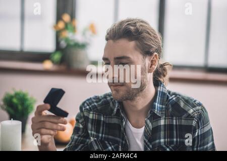 Young man looking at wedding ring box Banque D'Images