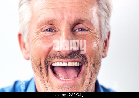 Close Up Studio Shot of mature Man Against White Background Laughing at Camera Banque D'Images