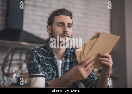 Jeune homme aux cheveux longs à maintenir les différentes cartes en papier Banque D'Images