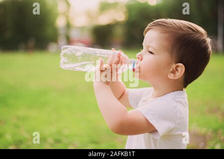 Beau bébé boit de l'eau propre à partir d'une bouteille sur une journée ensoleillée dans la nature Banque D'Images