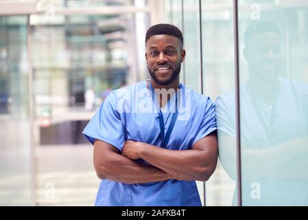 Portrait Of Male Doctor Wearing Scrubs debout dans la construction de l'hôpital moderne Banque D'Images