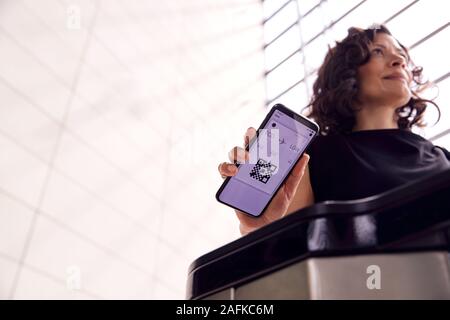 Businesswoman In Airport Departure Lounge numérique Numérisation d'embarquement sur téléphone intelligent Banque D'Images