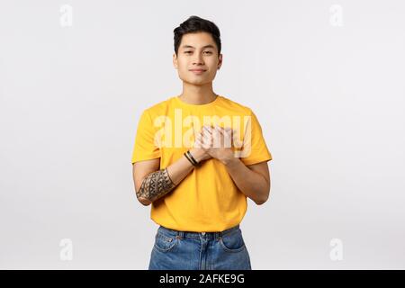 Touché, rêveur beau jeune mec asiatique avec des tatouages, porter des t-shirt jaune, chérir moment de tendresse avec ma copine valentines day, smiling Banque D'Images