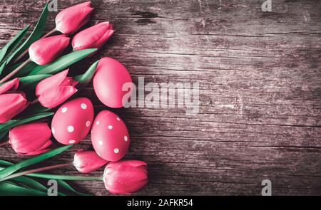 Oeufs de Pâques et rouge tulipe rose fleur sur table en bois vintage à partir de ci-dessus. Vacances de Pâques et de printemps conception d'arrière-plan. Vue d'en haut. Banque D'Images