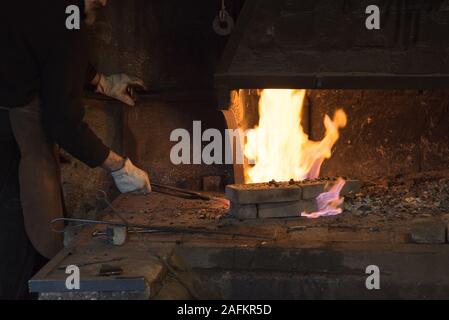 Ungersheim, Haut-Rhin / France - 13. Décembre, 2019 : Un forgeron travaillant le fer et l'acier dans une ancienne forge et forge Banque D'Images