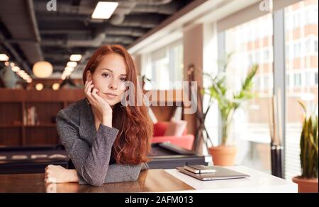 Portrait de façon décontractée habillé Young Businesswoman Working at Desk en milieu de travail moderne Banque D'Images