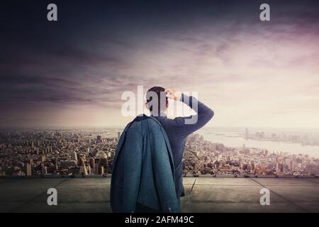 Vue arrière du pensive businessman sur le toit d'un gratte-ciel en regardant les toits de la ville. Gérant dynamique, de plus en plus d'inspiration pour de futures p Banque D'Images