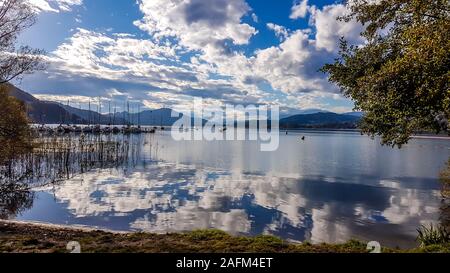 Un quai avec des bateaux sur le lac capturés pendant la golden hour. Dans l'arrière, il y a beaucoup de chaînes de montagnes. Les arbres sont golden tournant lentement. La surface Banque D'Images