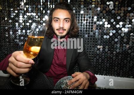 Jeune homme bien habillé cheering up avec flûte de champagne at party Banque D'Images