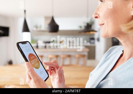 Mature Woman Using Digital Tablet App sur le contrôle de la température du chauffage central dans la maison Banque D'Images