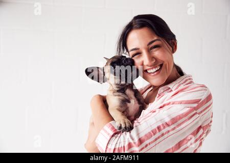 Studio Portrait Of Smiling Young Woman Holding affectueux chiot Bouledogue Français Banque D'Images