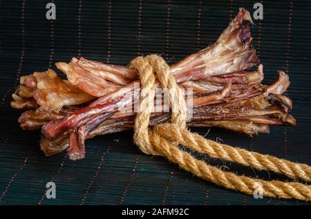 Boeuf séché tendon arrière. Gâteries pour chiens à mâcher naturel sur un fond sombre. Tir au niveau des yeux. Vue de côté. Espace libre pour le texte. Banque D'Images