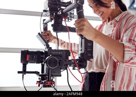 Vidéographe femelle avec caméra vidéo en continu en film Tournage Montage Cam Studio blanc Banque D'Images