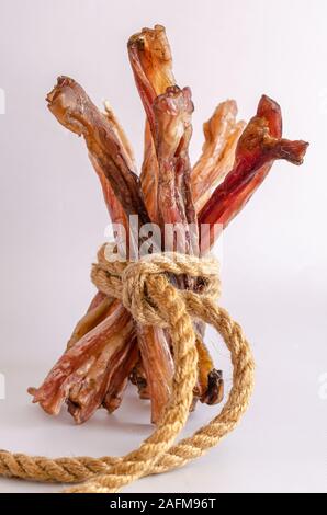 Une pile de tendons de boeuf séché sur un fond clair. Gâteries pour chiens sains déshydraté. Mâcher de la traite. Les tendons de boeuf. Version verticale de la photo. Banque D'Images