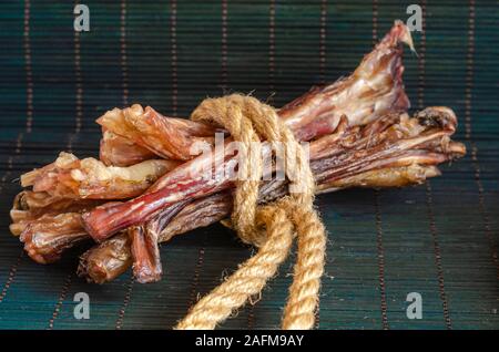 Un groupe de bœuf séché tendon arrière. Close-up Natural de mâcher de gâteries pour chiens sur un fond sombre. Tir au niveau des yeux. Vue de côté. Espace libre pour le texte. Banque D'Images