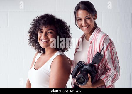 Portrait Of Smiling Female Photographer Holding Camera avec Modèle en Studio Portrait Session Banque D'Images