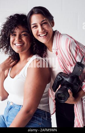 Portrait Of Smiling Female Photographer Holding Camera avec Modèle en Studio Portrait Session Banque D'Images