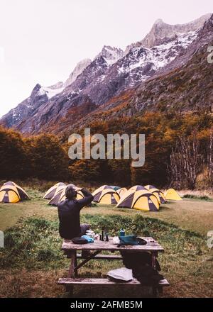 Camping l'homme assis à côté de montagnes et enjoying view Banque D'Images