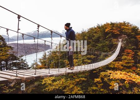 Homme debout sur le pont suspendu de montagne Banque D'Images