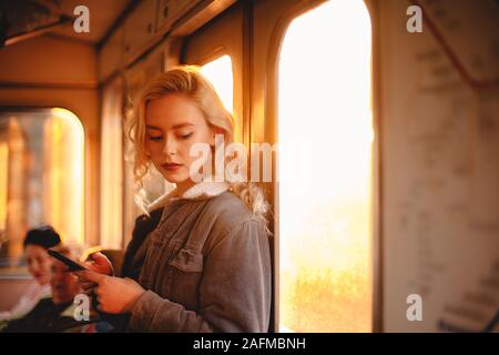 Jeune femme à l'aide de smart téléphone portable en voyage en métro Banque D'Images