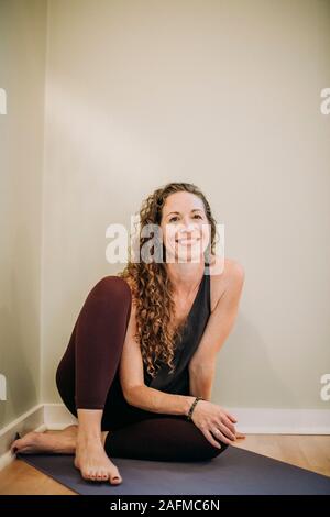 Portrait of smiling woman in yoga clothes sur tapis dans un studio Banque D'Images