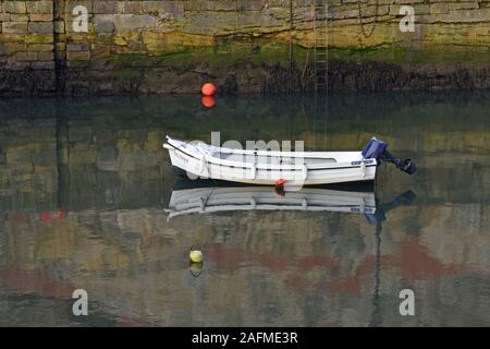 Petit bateau solitaire à Dysart Harbour dans le fifre, reflétée dans l'eau encore avec mur du port en arrière-plan. Banque D'Images