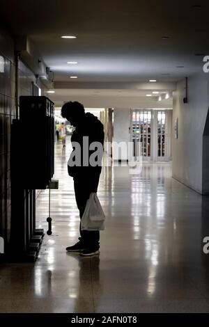 Un homme sans abri souffrant de troubles mentaux affamant au téléphone Banque D'Images