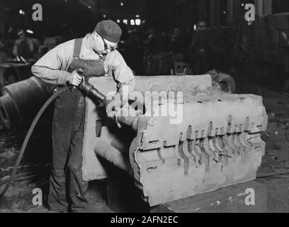 Un travailleur d'usine nettoie un casting sur un étage de la fonderie à Milwaukee, Wisconsin, ca. L'année 1930. Banque D'Images