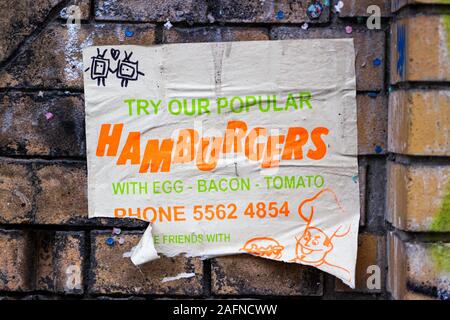 Hamburger déchirés place ad sur mur de brique jaune à Berlin, Allemagne Banque D'Images