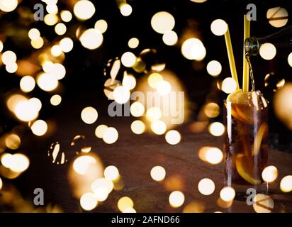 Barman prépare cocktail Cuba libre dans un grand verre sur le fond sombre. Shallow DOF avec lumières bokeh festive Banque D'Images