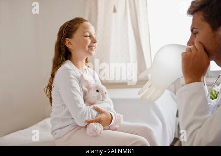 Médecin Blowing up gant en caoutchouc dans un ballon pour sa jeune patiente. Banque D'Images